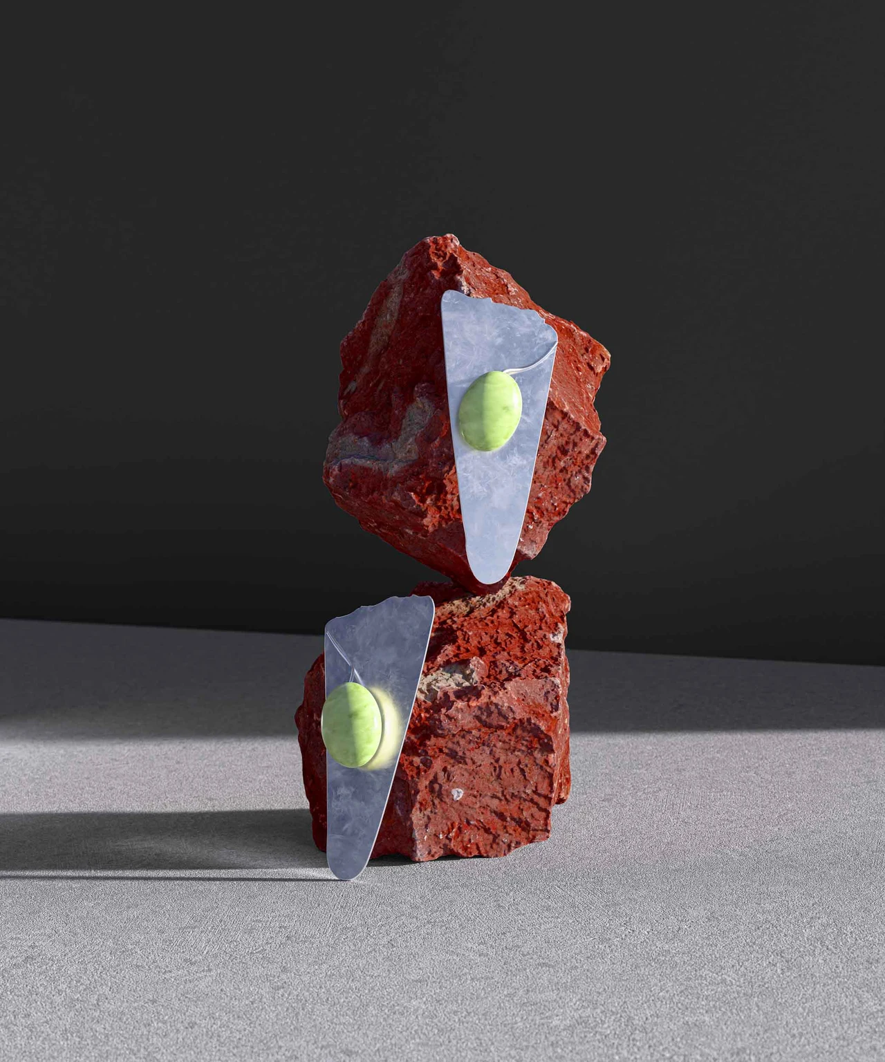 Two silver jewelry pieces with lime-green details sit on red rock fragments against a gray background under side lighting.