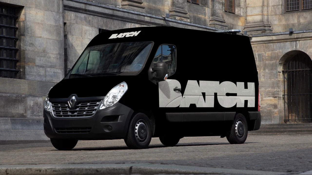 Black van parked on a street of historic architecture displays a large white BATCH wordmark on its side and a smaller version above the windshield.
