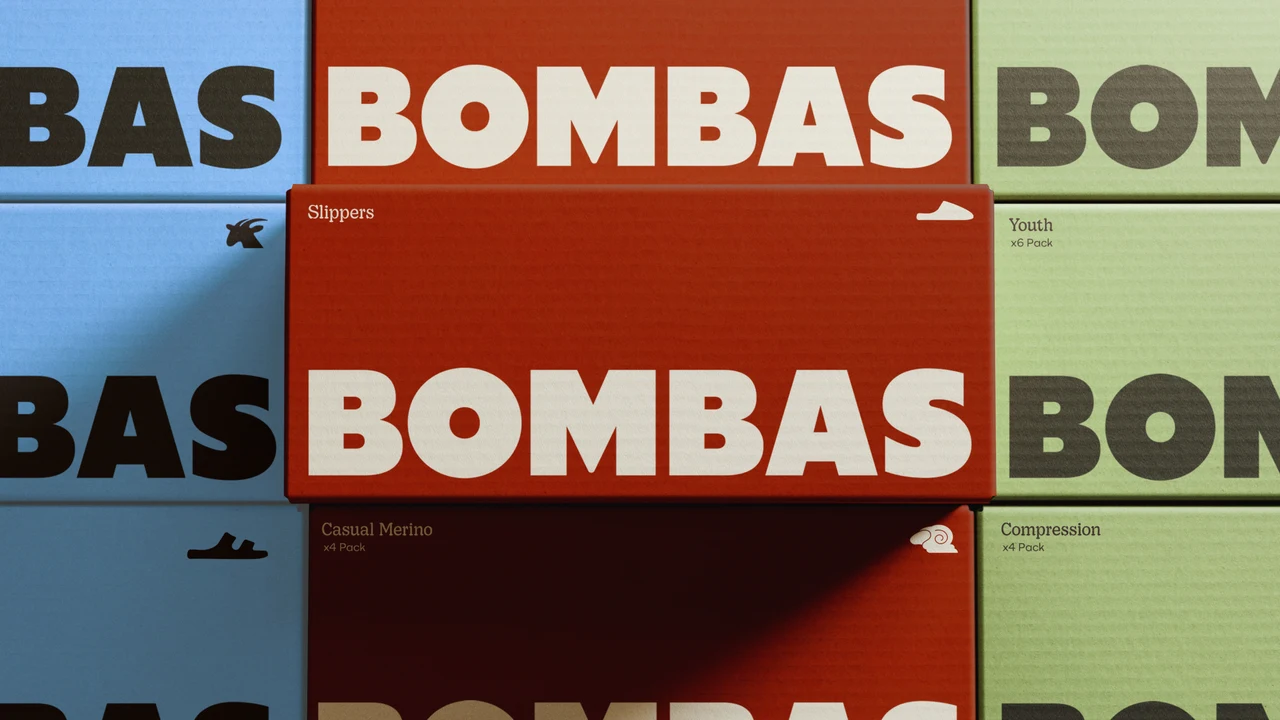 Stacked Bombas boxes in blue, red and green, each printed with a large BOMBAS wordmark, small product icons and labels such as Slippers, Youth, Casual Merino and Compression.