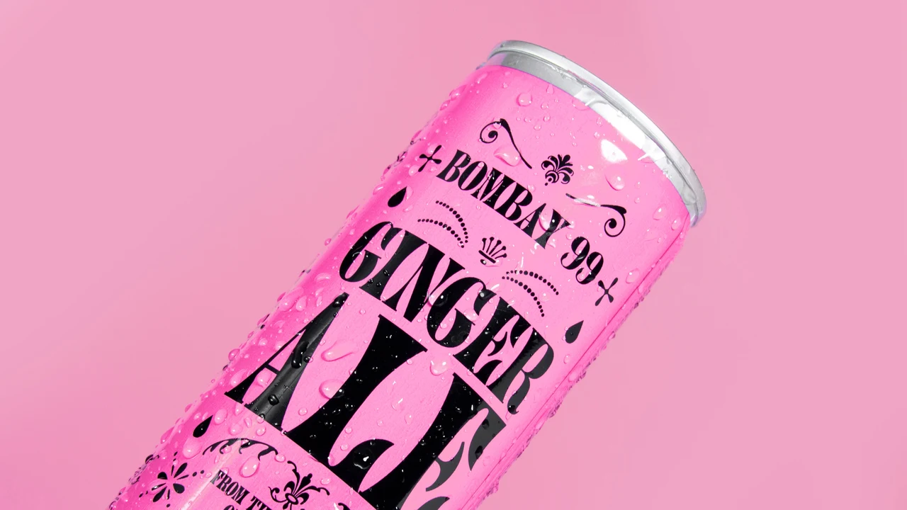Pink Ginger Ale can appears diagonally in close-up, with condensation drops over tall black lettering and ornaments against a pink background.