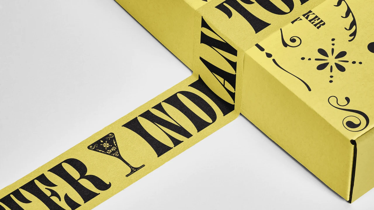 Detail of a yellow box sealed with matching tape and large repeated black lettering, revealing ornaments on the lid.