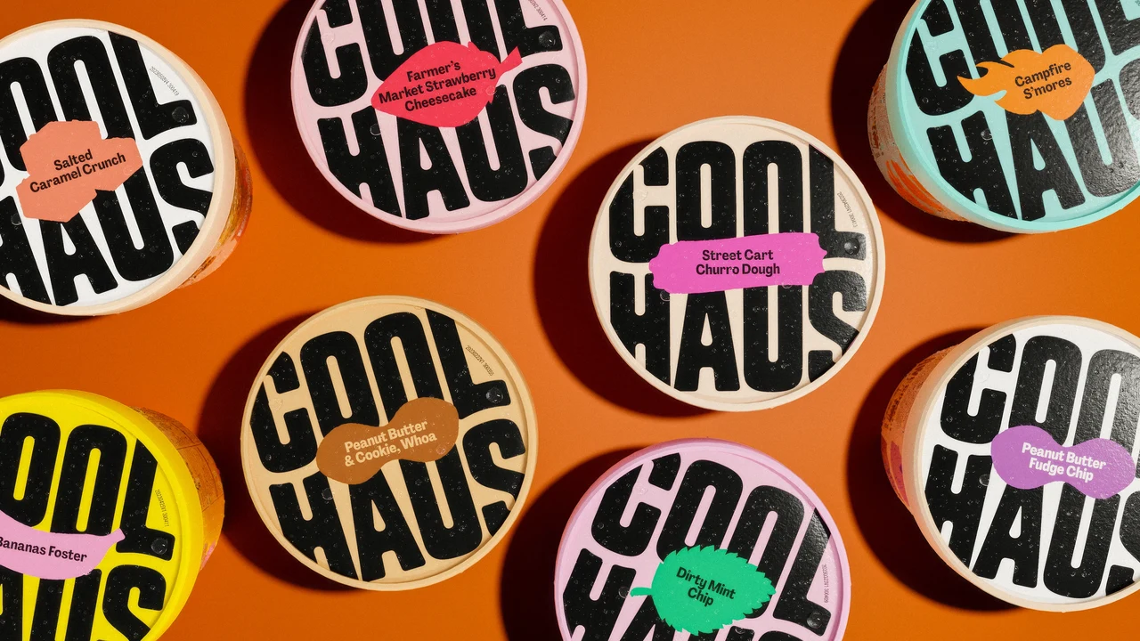 Overhead view of several Coolhaus ice cream lids on orange, featuring enlarged black branding and colored labels distinguishing flavors.