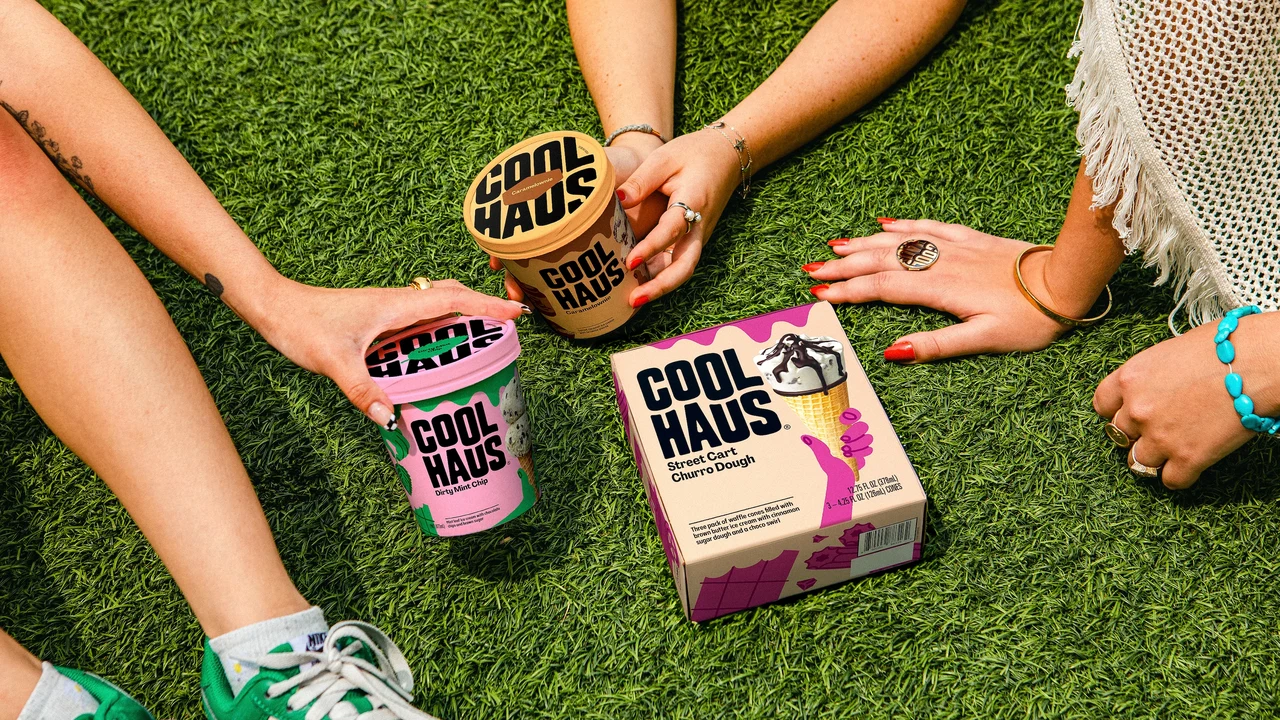 People seated on grass hold Coolhaus tubs beside a cone box; the framing highlights arms, legs and sneakers around the products.