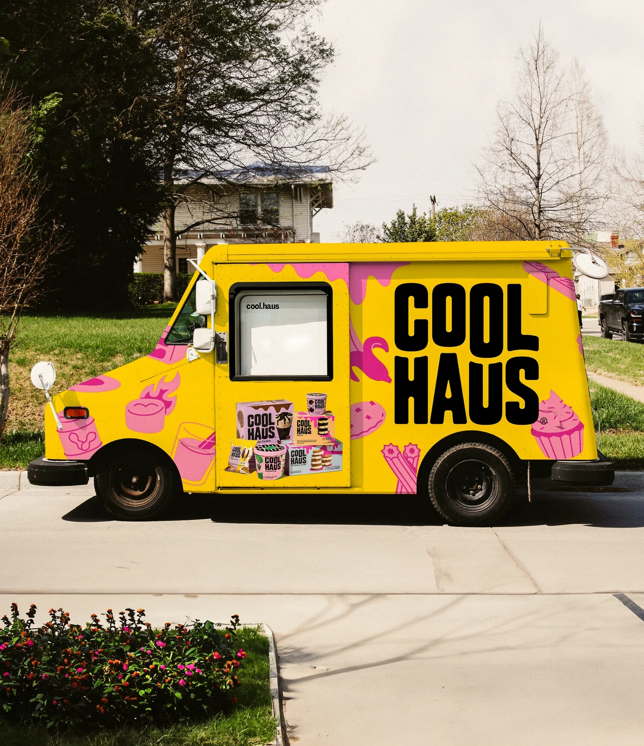 Yellow Coolhaus food truck parked outdoors features an enormous black wordmark, pink illustrations and a menu beside the serving window.
