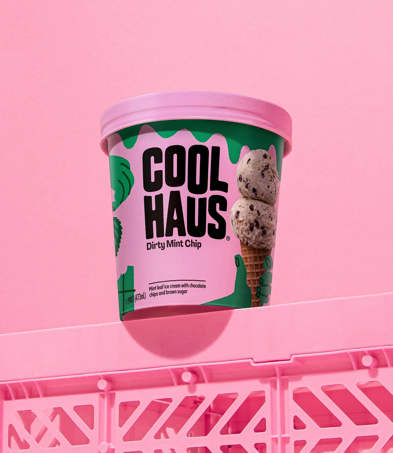 Pink and green Coolhaus Dirty Mint Chip tub photographed in a pink monochromatic composition above an openwork plastic crate.