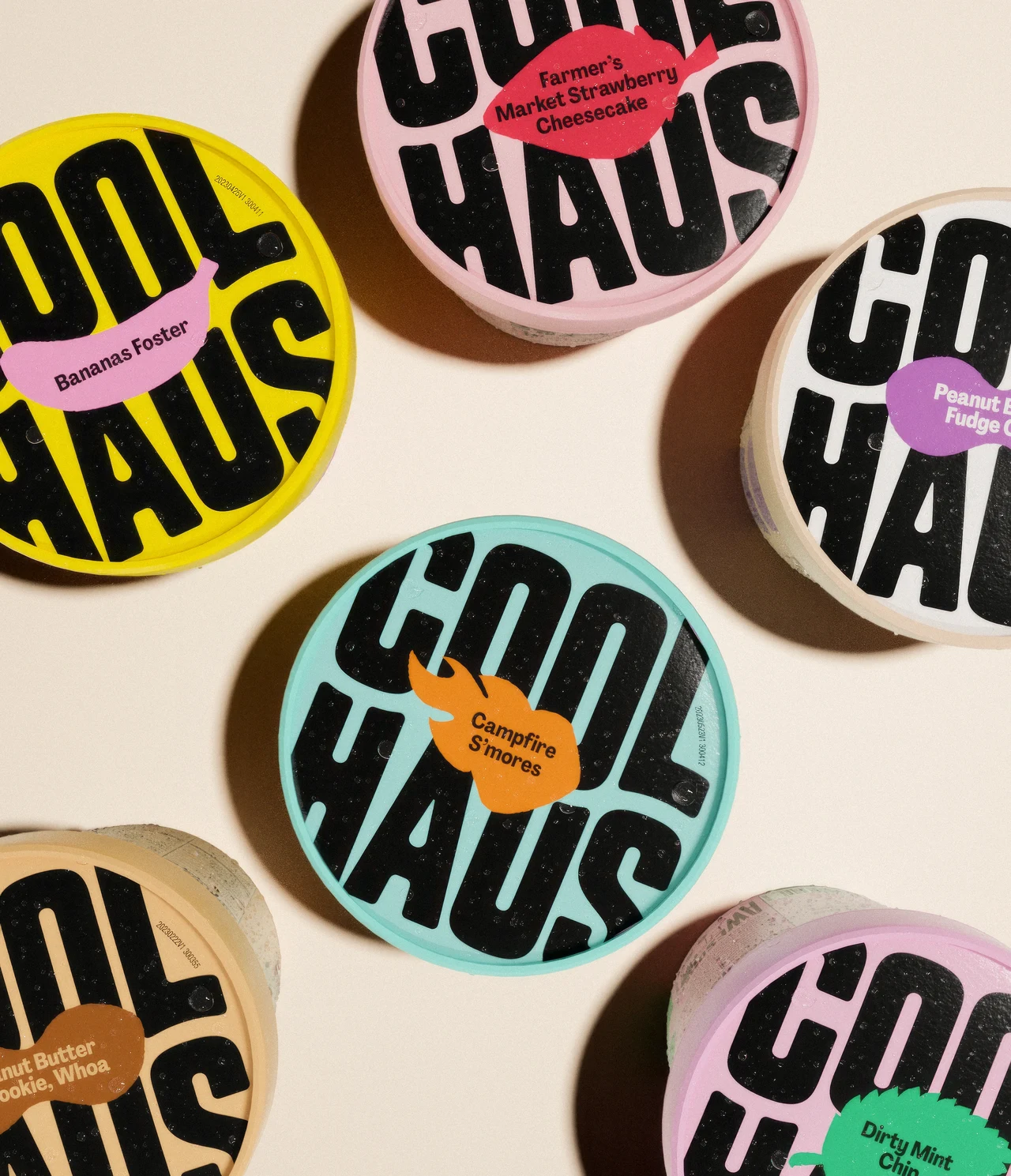 Round Coolhaus lids in yellow, pink, blue and cream form an arrangement on a pale surface, with large black wordmarks and small flavor labels.