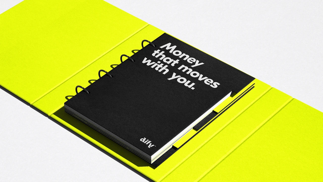 A black spiral notebook bearing Money that moves with you sits inside a lime-yellow folder.