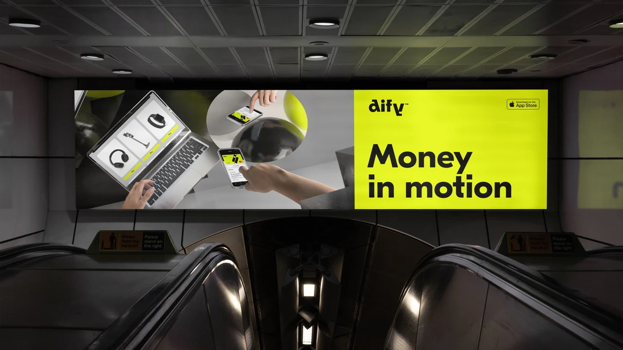 A horizontal billboard above escalators combines floating electronics with the phrase Money in motion on yellow.