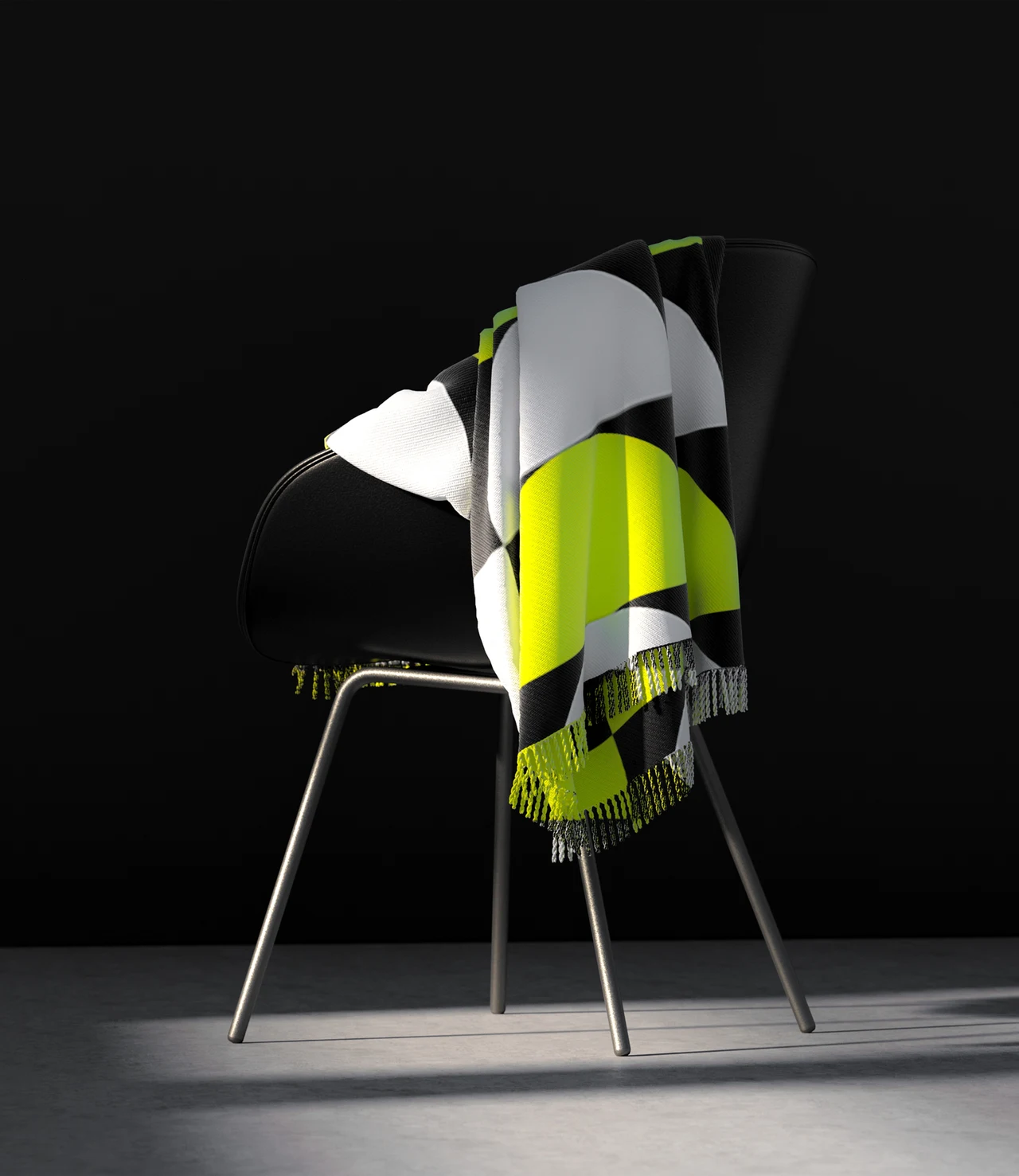 A blanket with black, white and yellow geometric graphics is draped over a black chair in a dark setting.