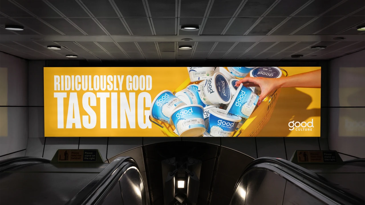 A yellow advertisement above an escalator combines “Ridiculously good tasting” copy with a composition of Good Culture tubs and a hand.