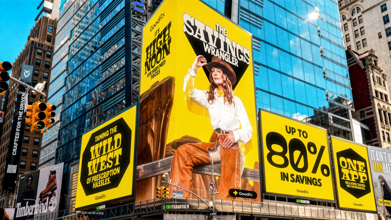 Wide view of yellow digital billboards on a glass tower: the cowgirl on a fence with The Savings Wrangler and It's High Noon for High Med Prices, flanked by Taming the Wild West, Up to 80% in Savings and One App.
