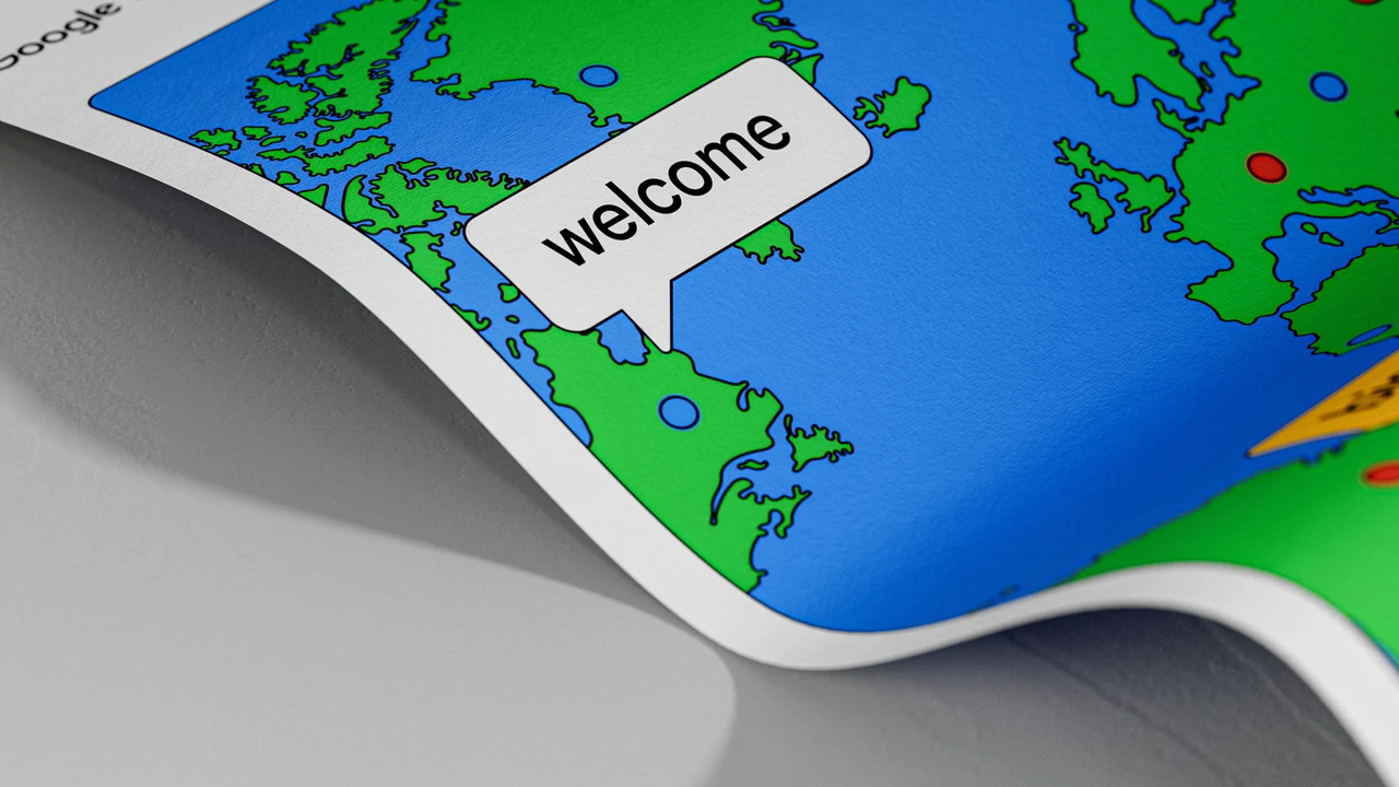 Close de um cartaz curvado apresenta mapa-múndi azul e verde com marcadores coloridos e um balão branco escrito “welcome”.