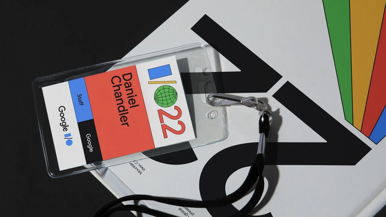 Crachá transparente com faixa vermelha e o nome Daniel Chandler apresenta a marca I/O 22 e etiquetas de função, preso a um cordão preto.