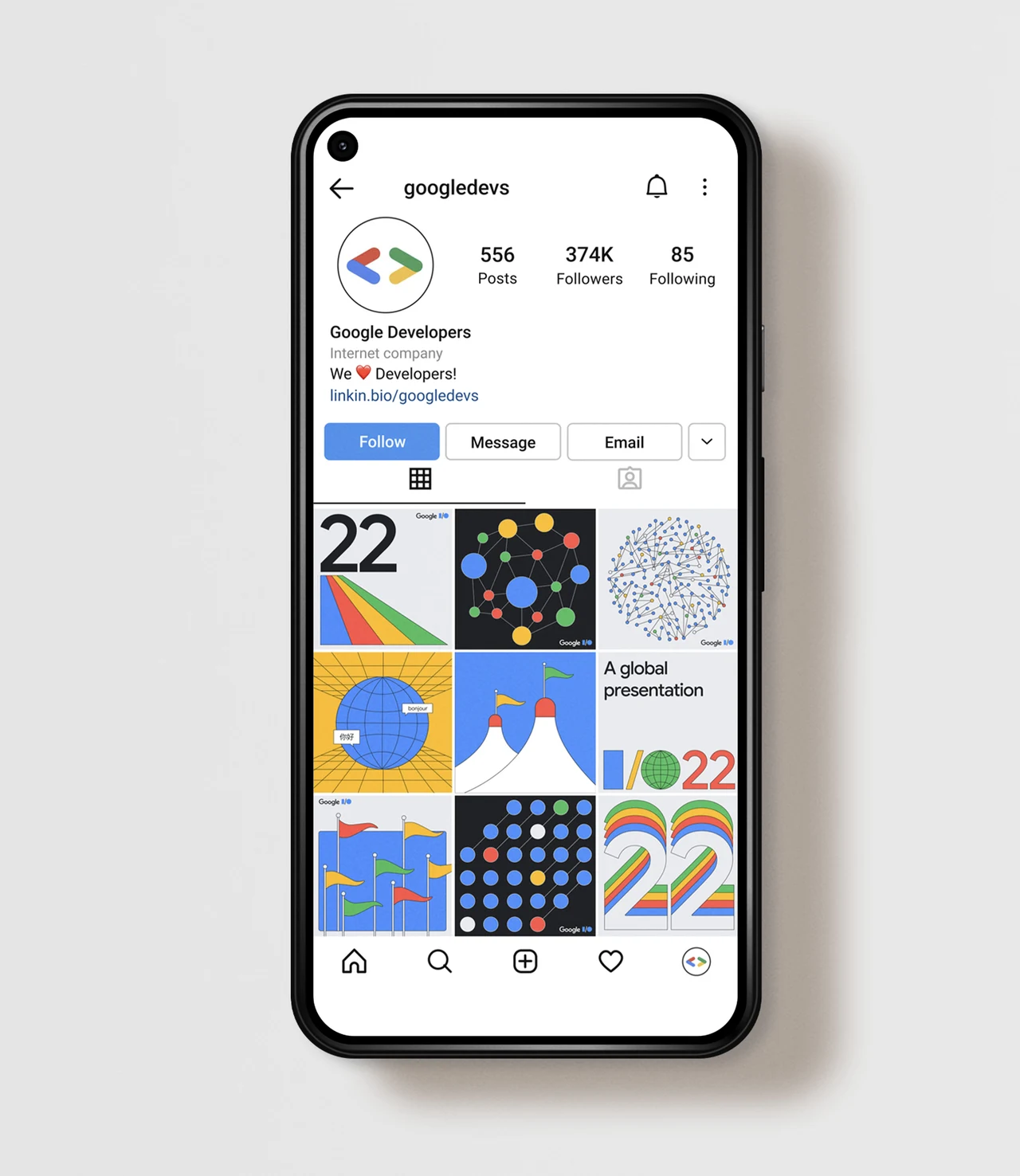 Celular mostra o perfil Google Developers com uma grade de publicações I/O 2022 que alterna números, círculos, bandeiras, globos e ilustrações coloridas.
