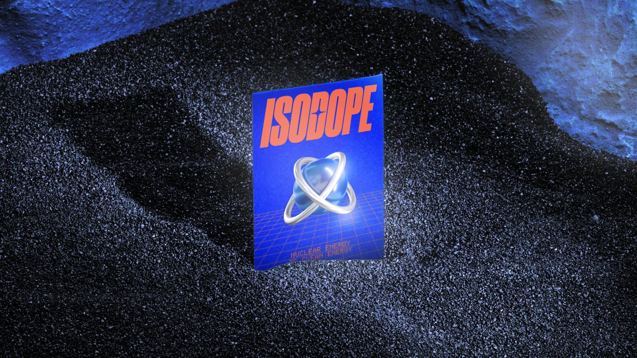 Peça impressa azul com logotipo Isodope laranja e símbolo atômico metálico fica fincada em grãos escuros, entre rochas iluminadas em azul.