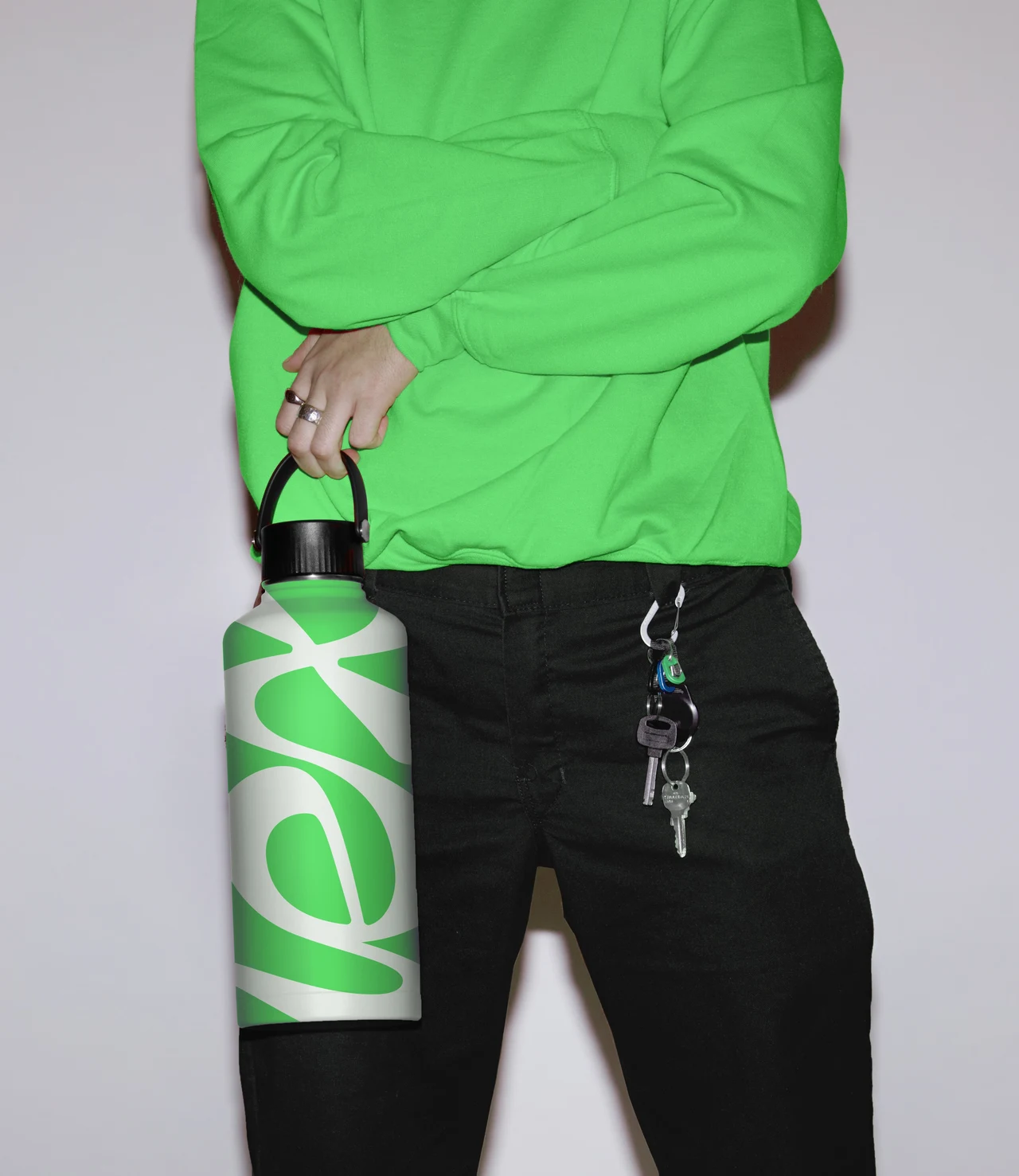 A cropped portrait shows a person in a green sweatshirt holding a metal bottle printed with the Lex wordmark, with keys hanging from black trousers.