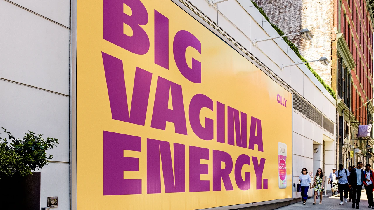 Yellow street-facade billboard displays Big Vagina Energy in oversized magenta letters with an OLLY package in the corner.