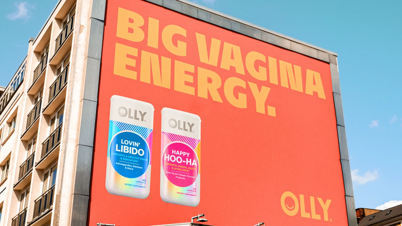 Large building advertisement displays Big Vagina Energy in yellow on orange beside Lovin Libido and Happy Hoo-Ha bottles.