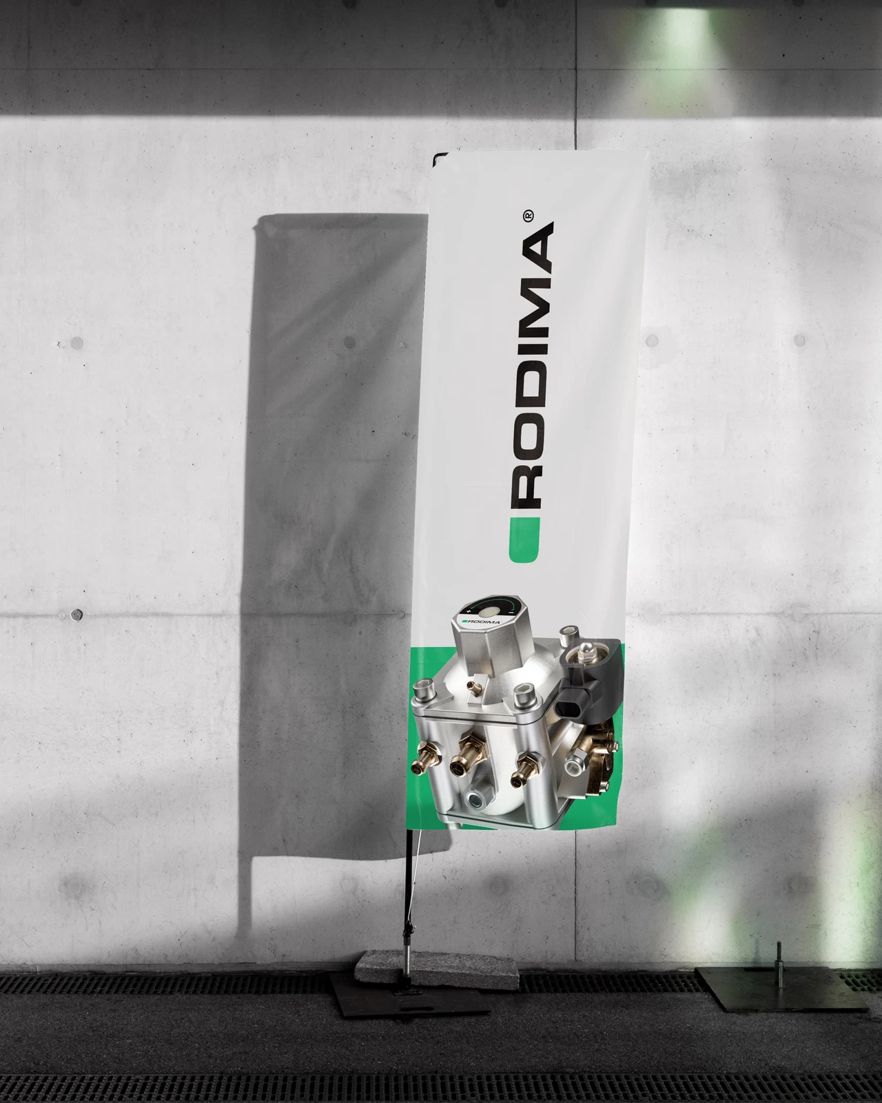 A vertical Rodima banner with a metallic component photograph and green branding is shown against a concrete wall with shadows.