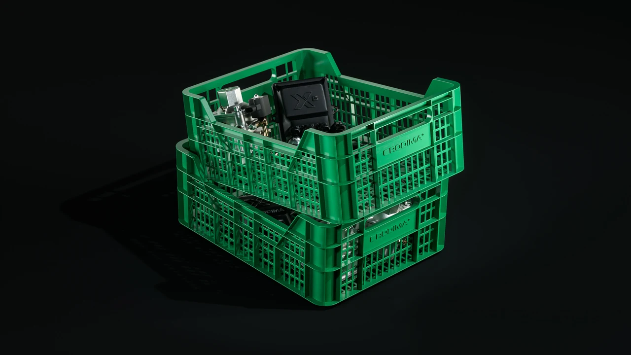 Two stacked green plastic crates hold automotive components in a lit composition against black.