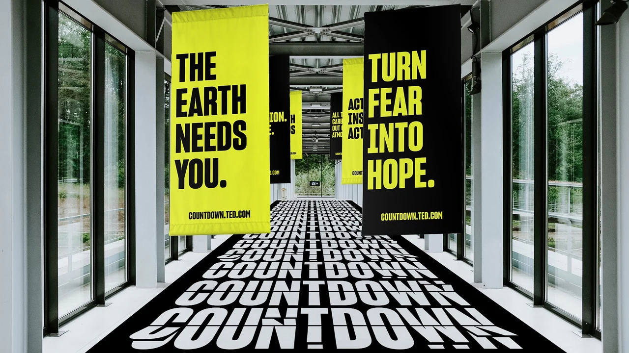Glass corridor is filled with vertical climate-message banners and a black floor covered in repeated white Countdown lettering.