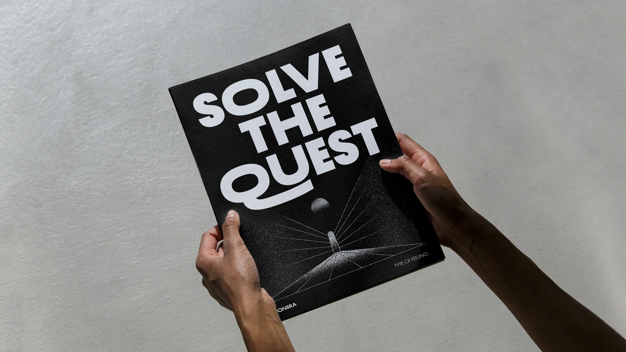 Two hands hold a black poster with “Solve the quest” in heavy white typography, accompanied by fine lines and a small sphere below.