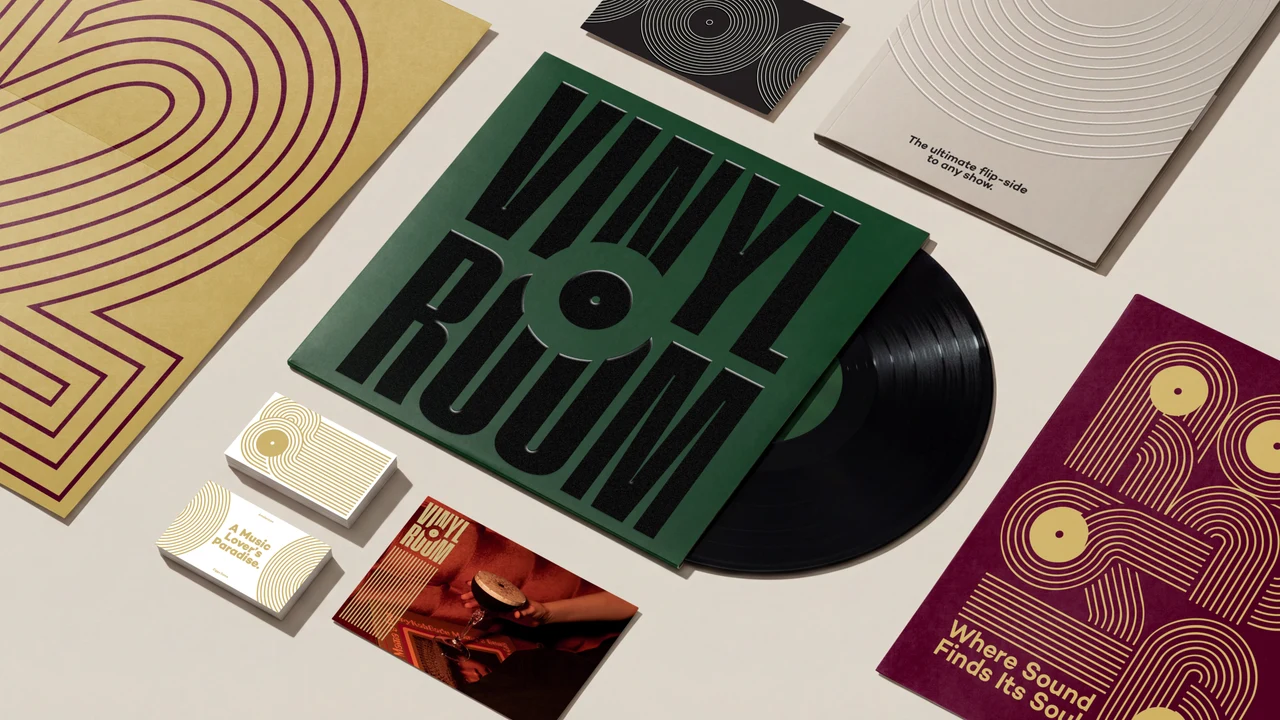 Flat lay of Vinyl Room print pieces: a green record sleeve with the black wordmark, a black record, business cards, postcards and gold and burgundy posters with concentric line patterns.