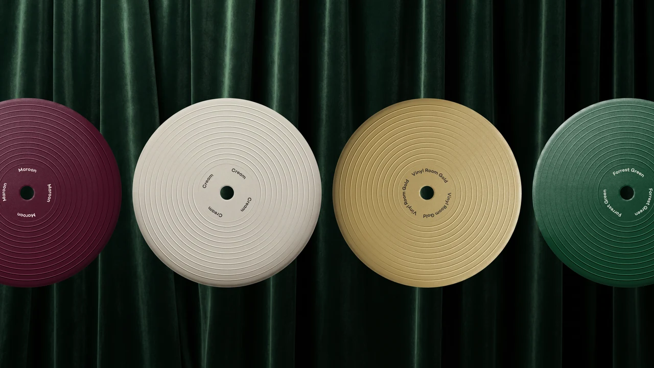 Four color swatches shaped like records in maroon, cream, Vinyl Room gold and forest green, set against a dark green velvet curtain.