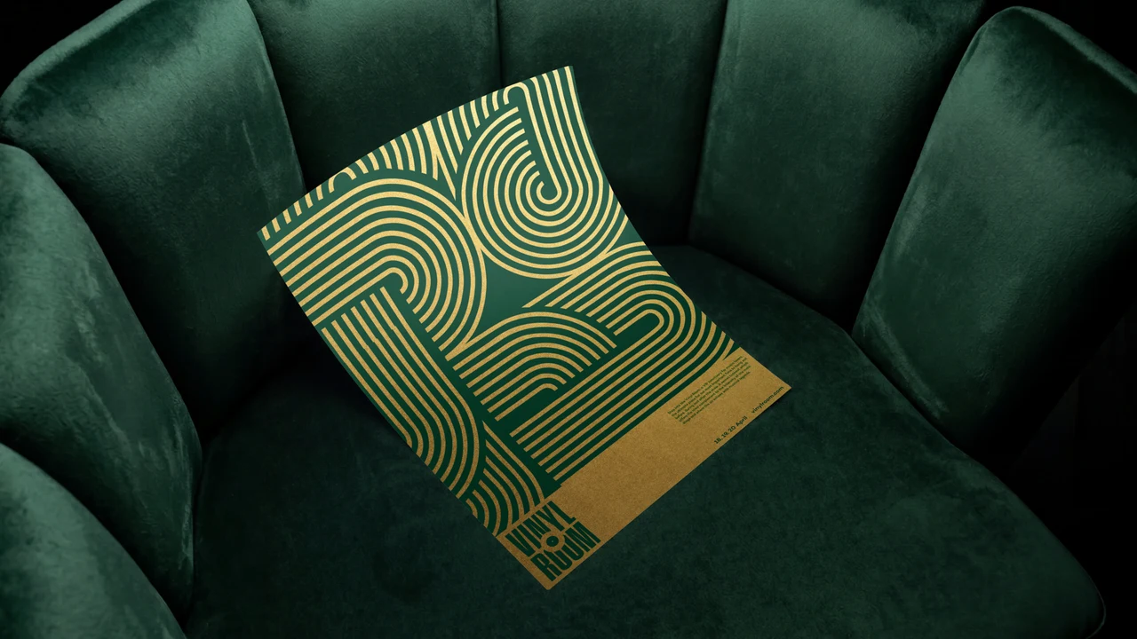 Green and gold poster with interlocking concentric line patterns and a small Vinyl Room logo, resting on a green velvet chair.